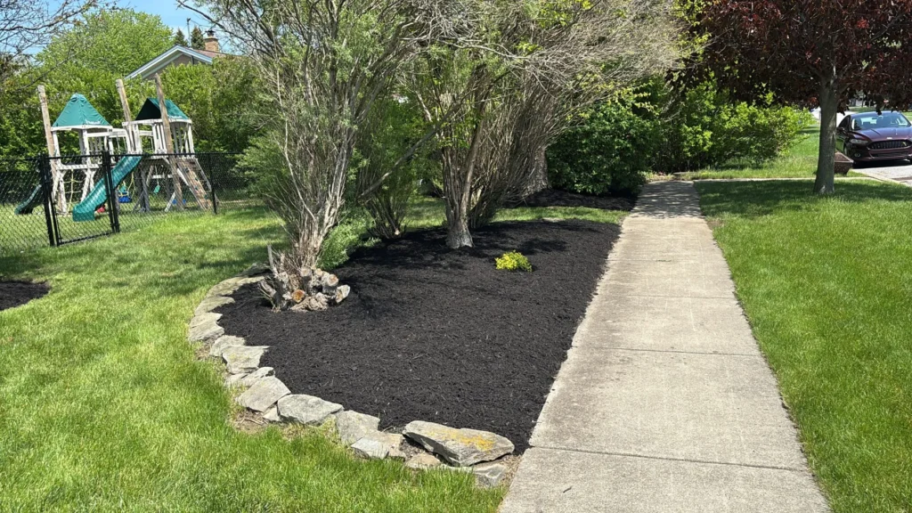 Stone-edged garden bed with boulders beside a front walkway