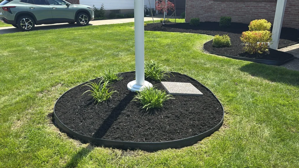 Freshly edged mulch bed around a flagpole in a Buffalo front lawn